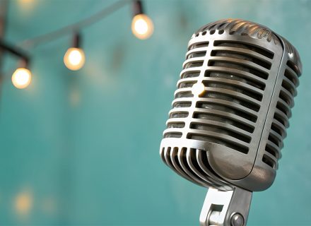 Old time microphone with a string of lights in the background.