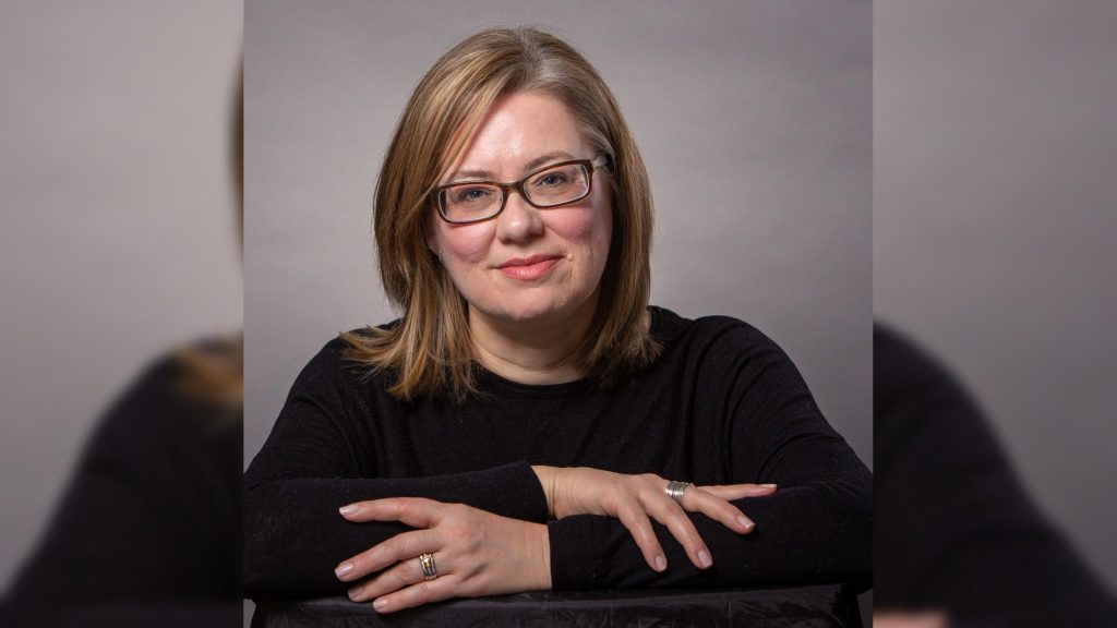 Photo of Jennifer. A woman wearing black glasses with thick lenses.