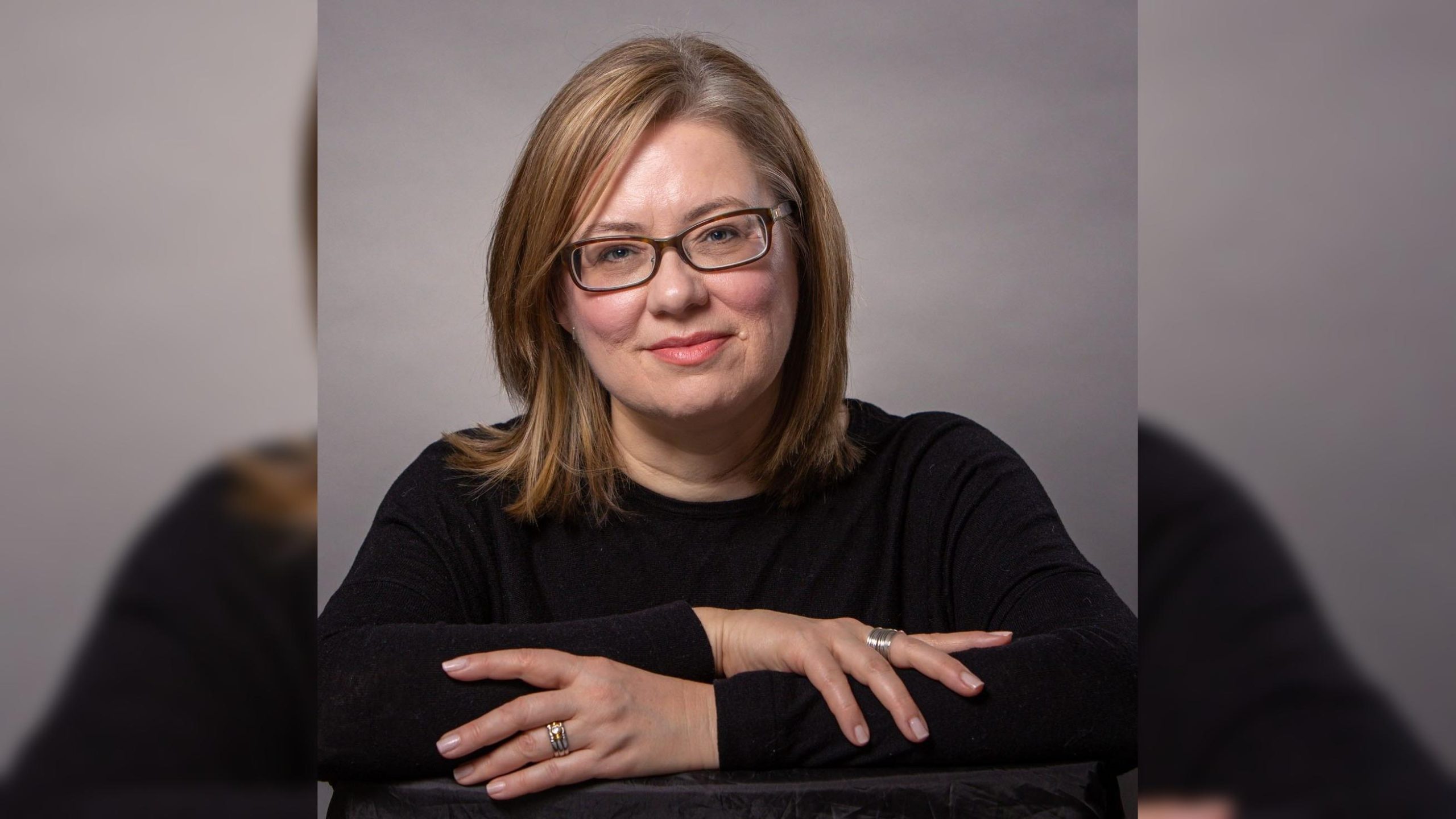 Photo of Jennifer. A woman wearing black glasses with thick lenses.