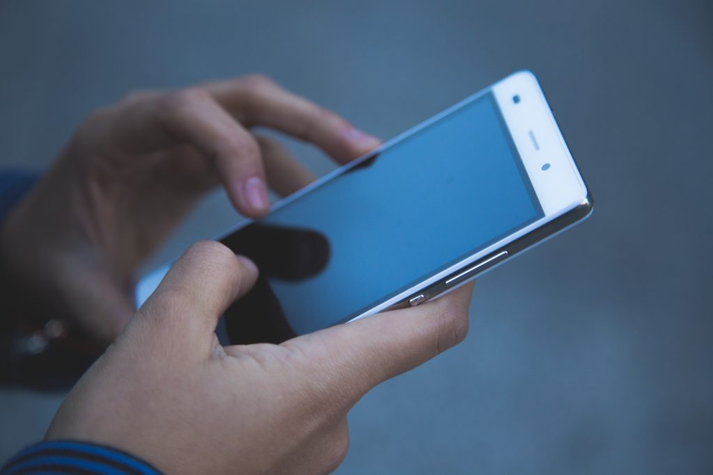 Hands holding a generic mobile phone.
